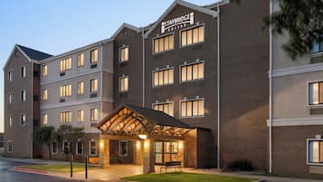 A Staybridge Suites hotel with a brick facade, multiple windows, and a well-lit entrance.
