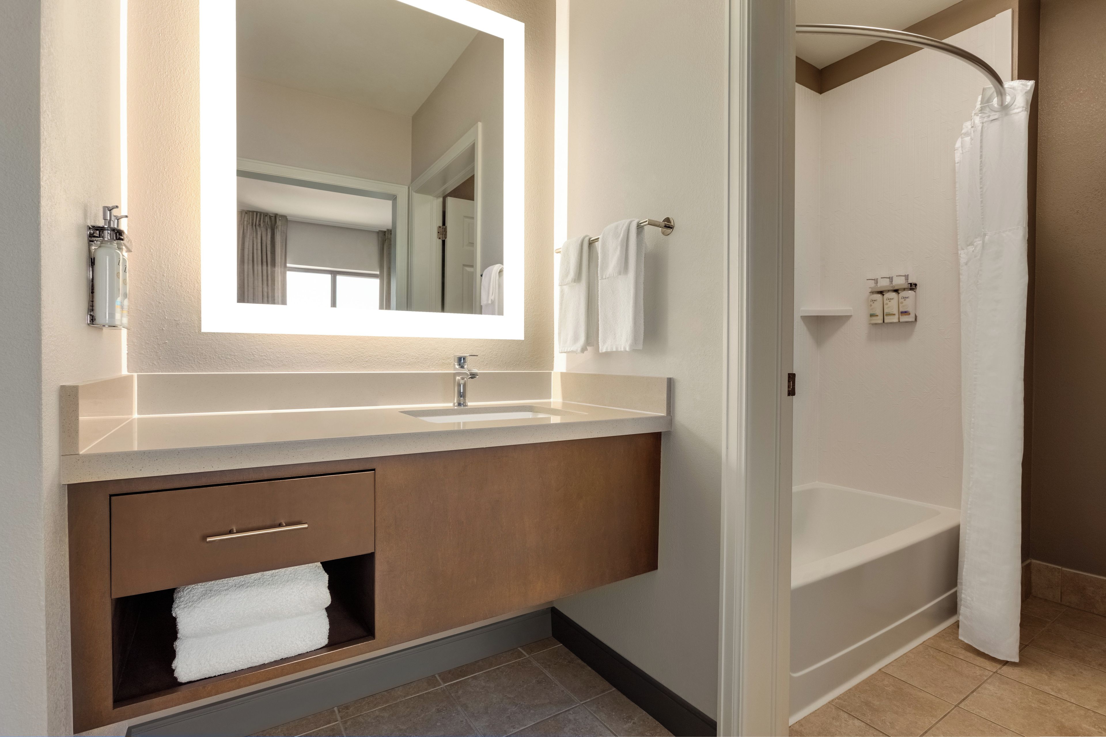 Un baño moderno con un espejo grande, un lavabo, una ducha y un perchero para toallas.