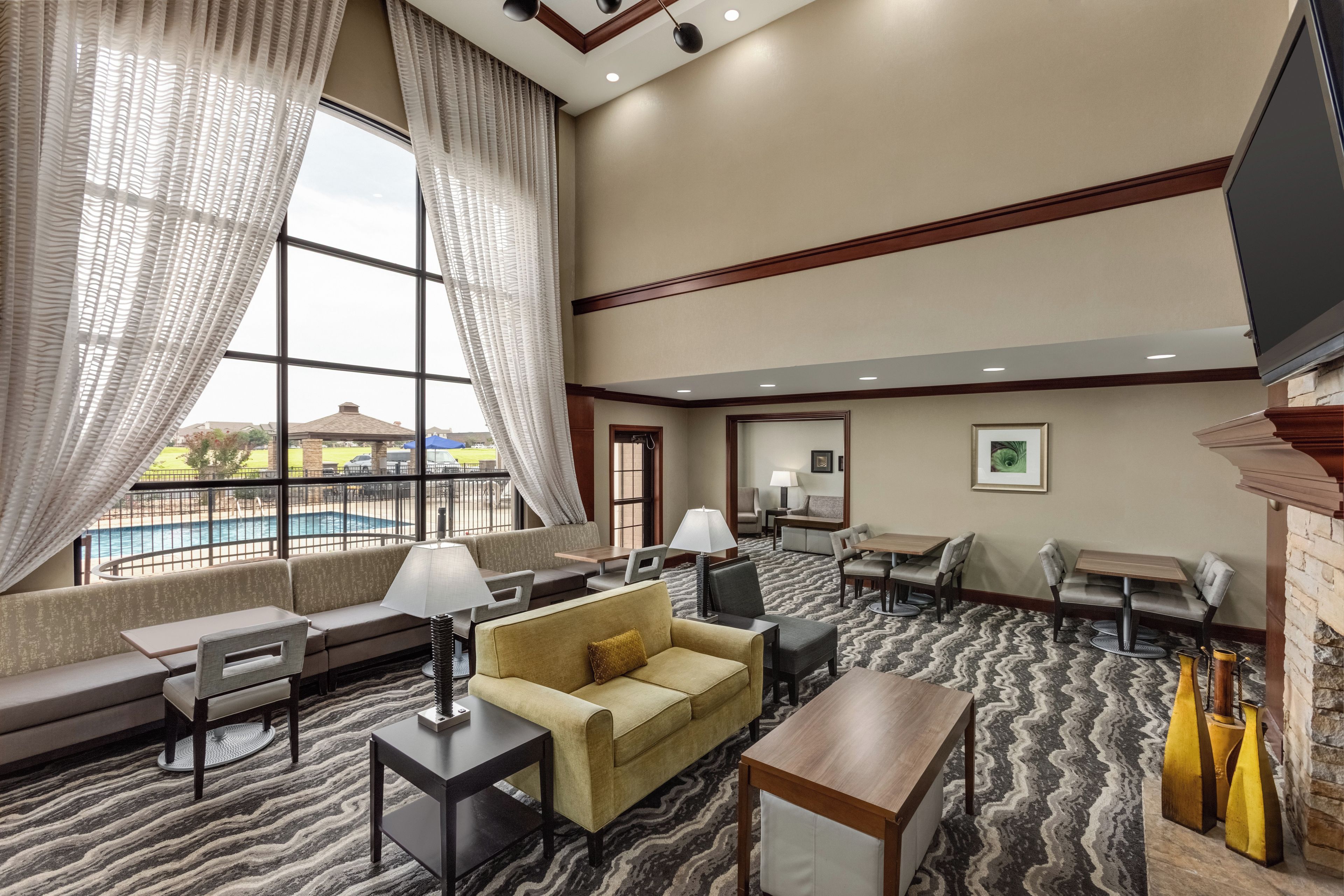 A hotel lobby with a pool view, seating areas, and a fireplace.