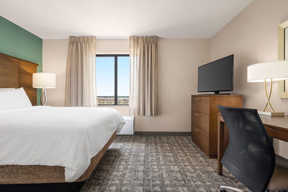 Una habitación de hotel con cama, escritorio, televisión y vistas de la ciudad.