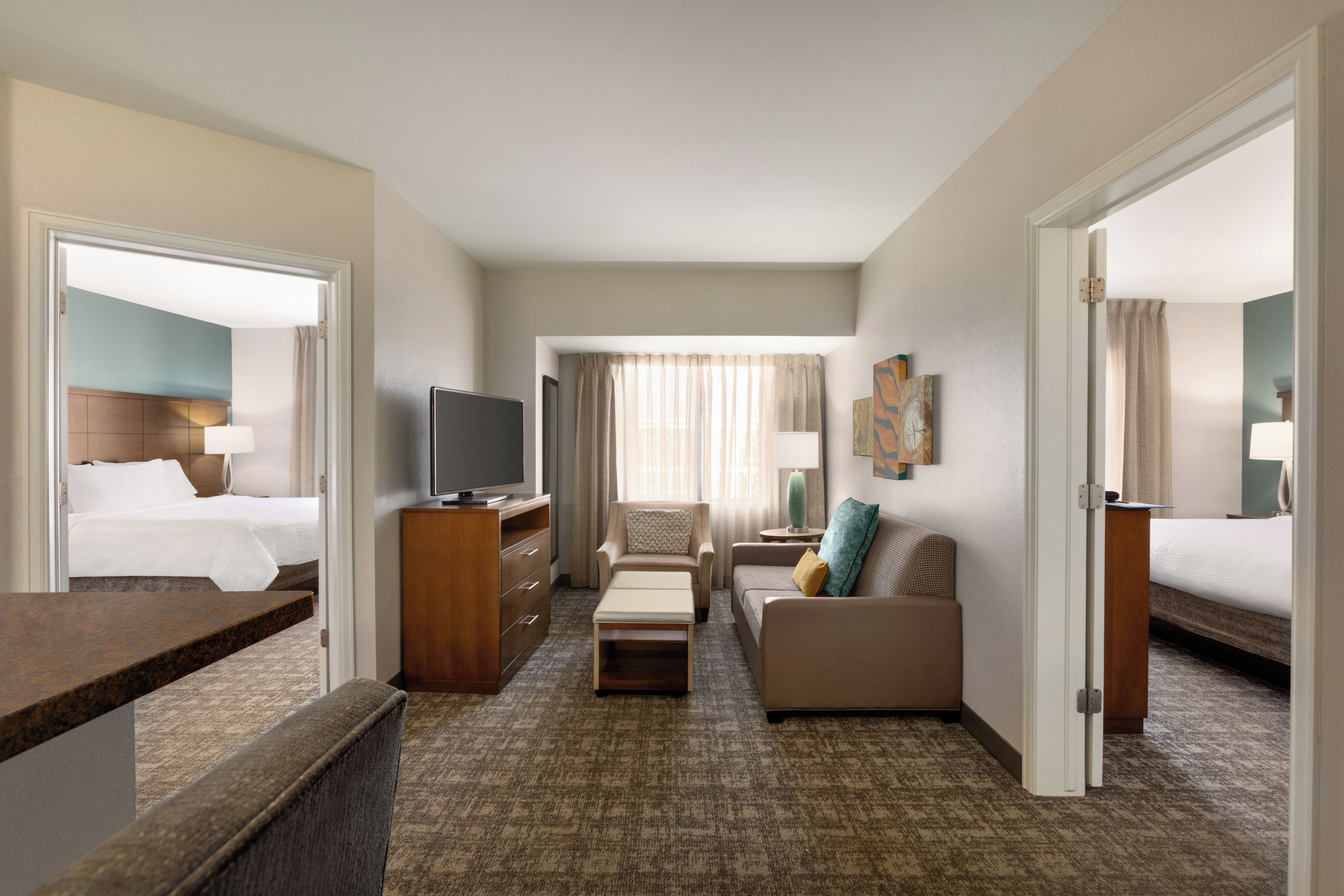 A hotel room with a bed, a TV, a desk, a sofa, and a chair.
