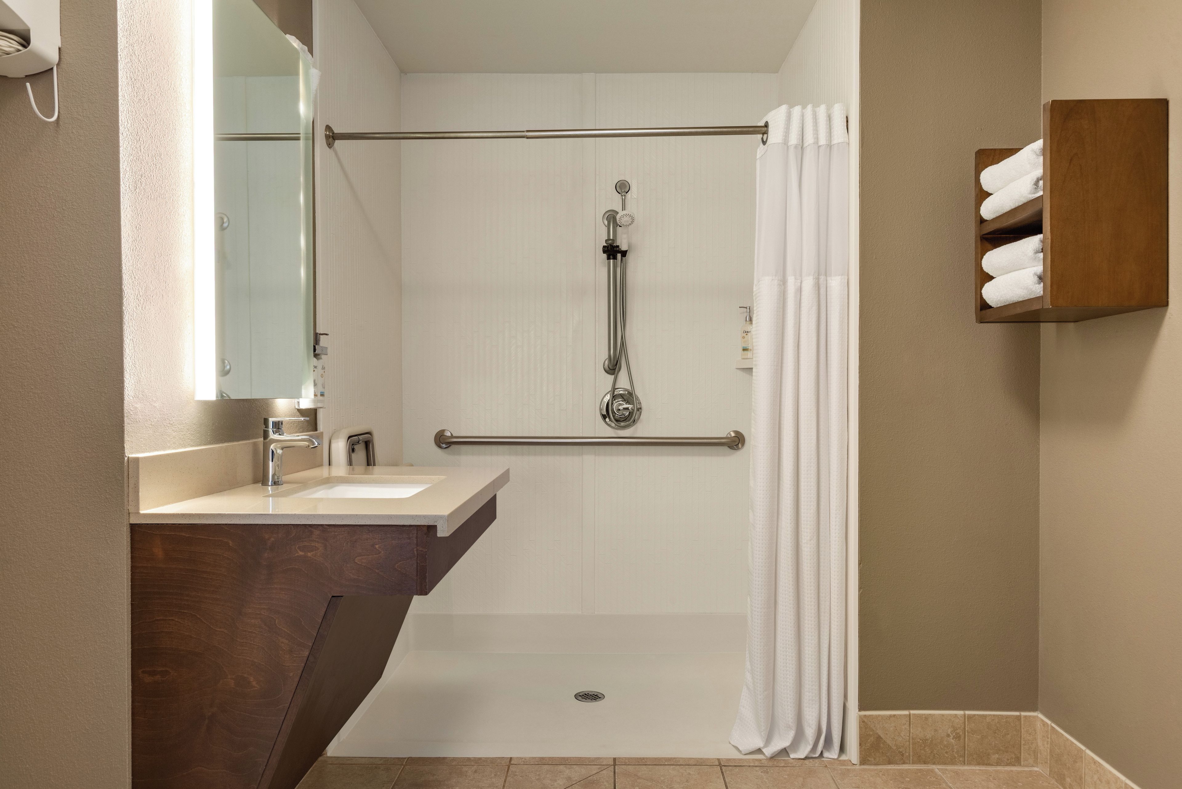 Un baño con ducha, lavabo, espejo y perchero.