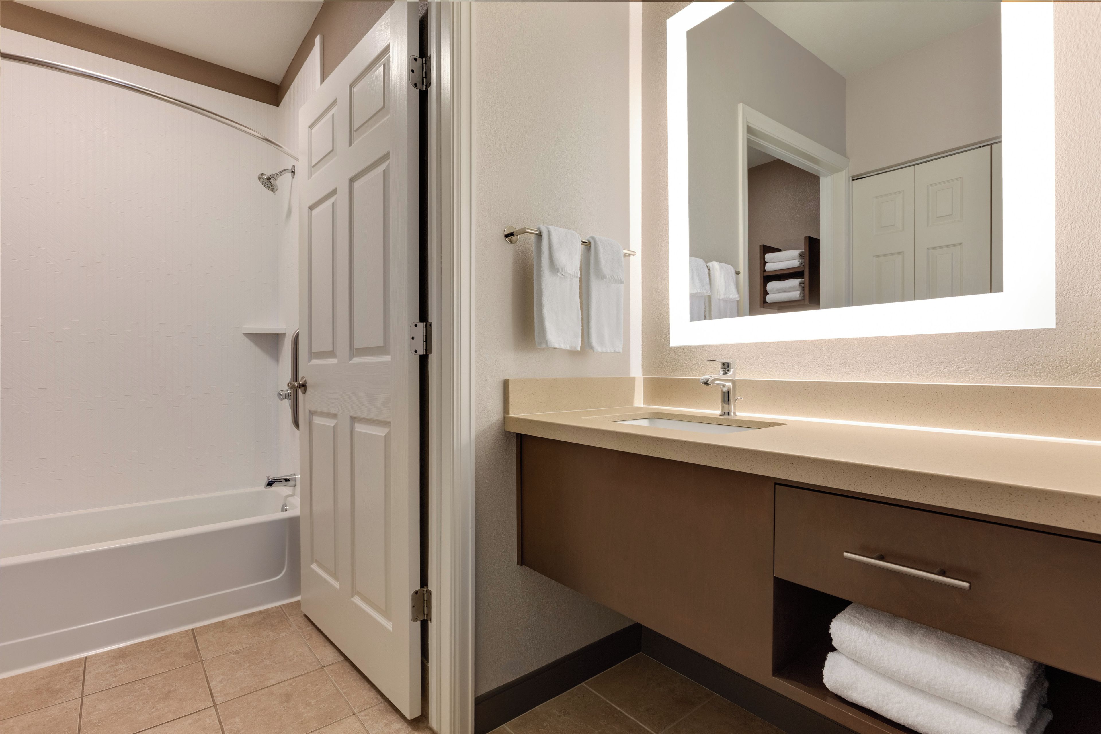 A bathroom with a bathtub, a sink, a mirror, and a towel rack.