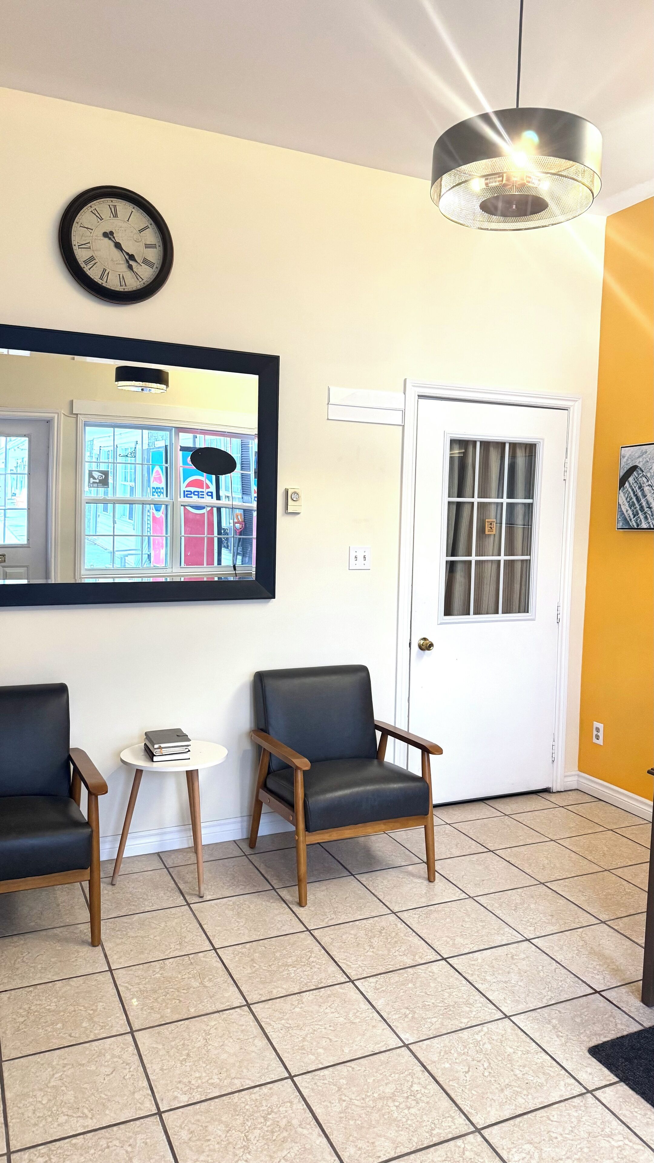 A waiting area with two chairs, a small table, a clock, and a door.