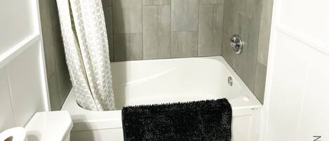 A bathroom with a bathtub, toilet, and shower curtain.