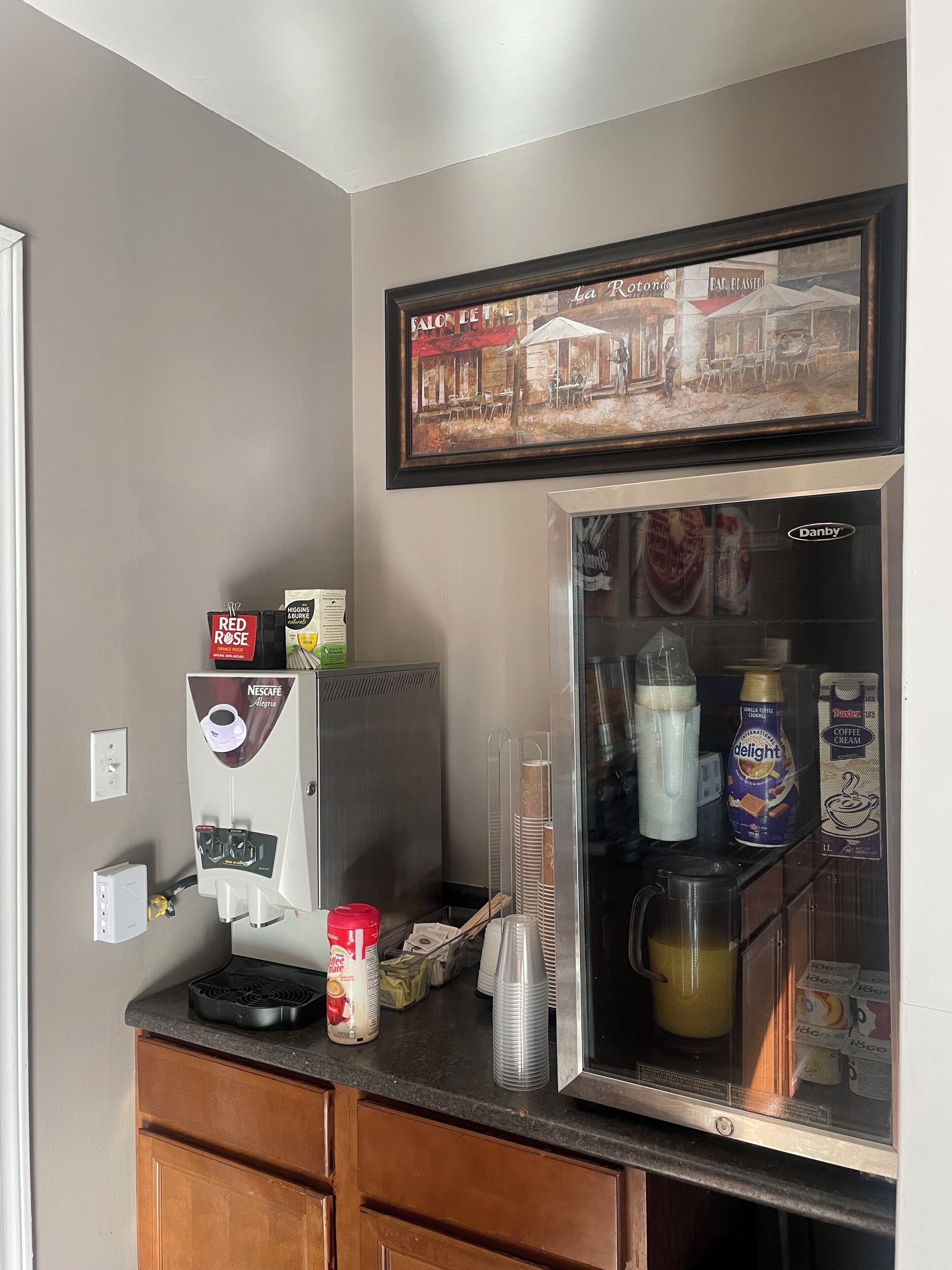 A kitchenette with a coffee machine, a refrigerator, and a coffee station.