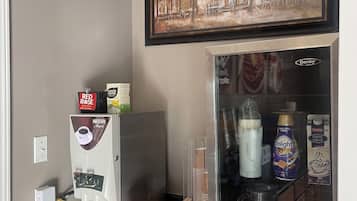 A kitchenette with a coffee machine, a refrigerator, and a coffee station.