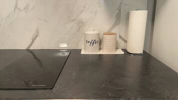 A kitchen counter with a coffee maker, two containers, and a paper towel holder.