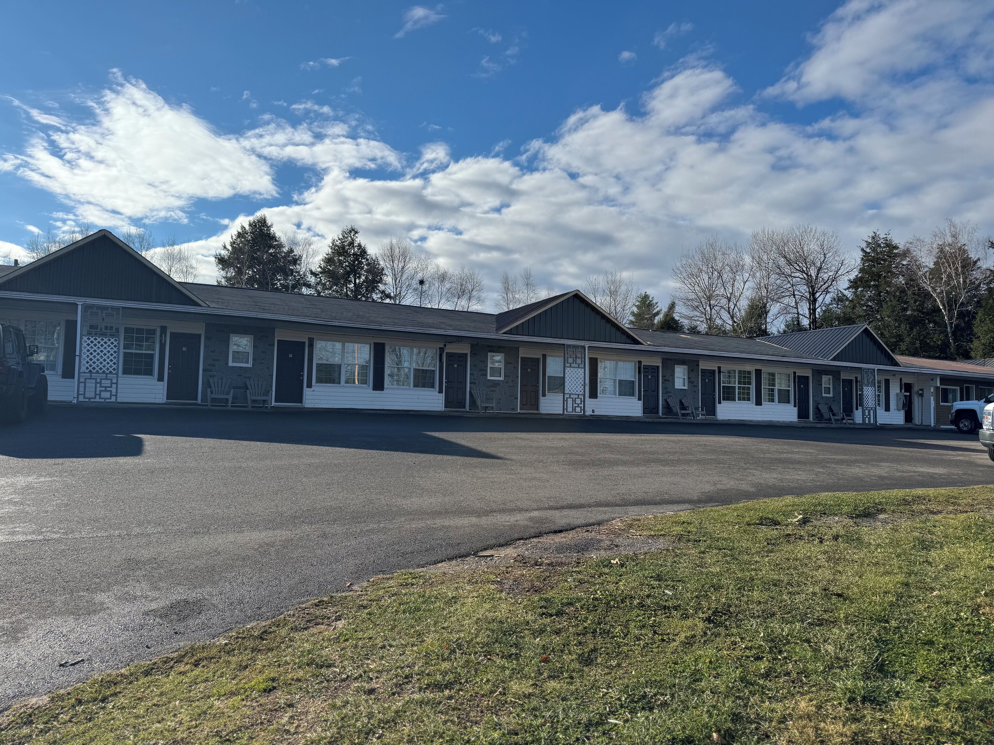 A row of motel-style buildings with a parking lot in front.