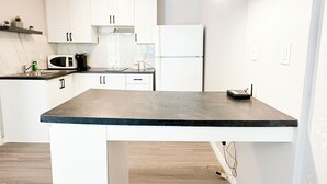 A modern kitchen with white cabinetry, a dark countertop, and pendant lighting.