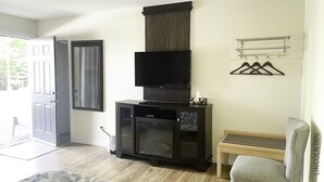 A living room with a flat-screen TV mounted on a cabinet, a bench, and a coat rack.