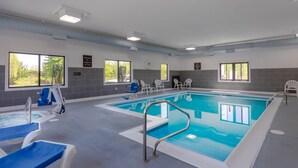 Une piscine à l’eau bleue, entourée de chaises longues blanches et d’une chaise de maître-nageur.
