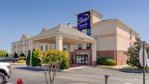 Un bâtiment de la chaîne Sleep Inn & Suites, avec un ciel dégagé, un parking et un potelet d’hydrant.