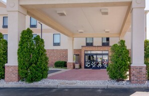 A hotel entrance with a covered walkway, brick facade, and a glass door entrance.
