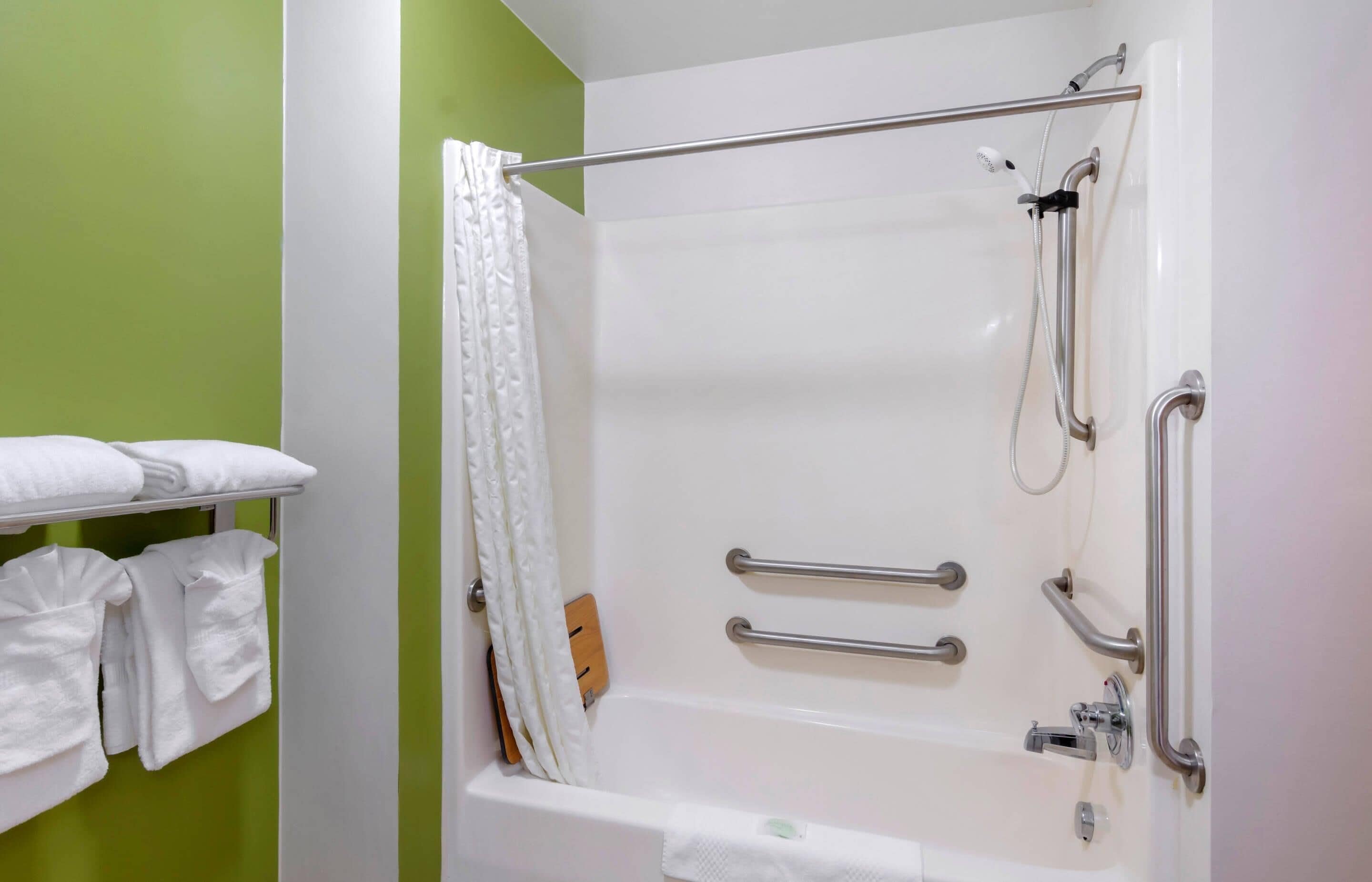 Une salle de bain équipée d’une baignoire, de barres d’appui et d’un porte-serviettes avec des serviettes.