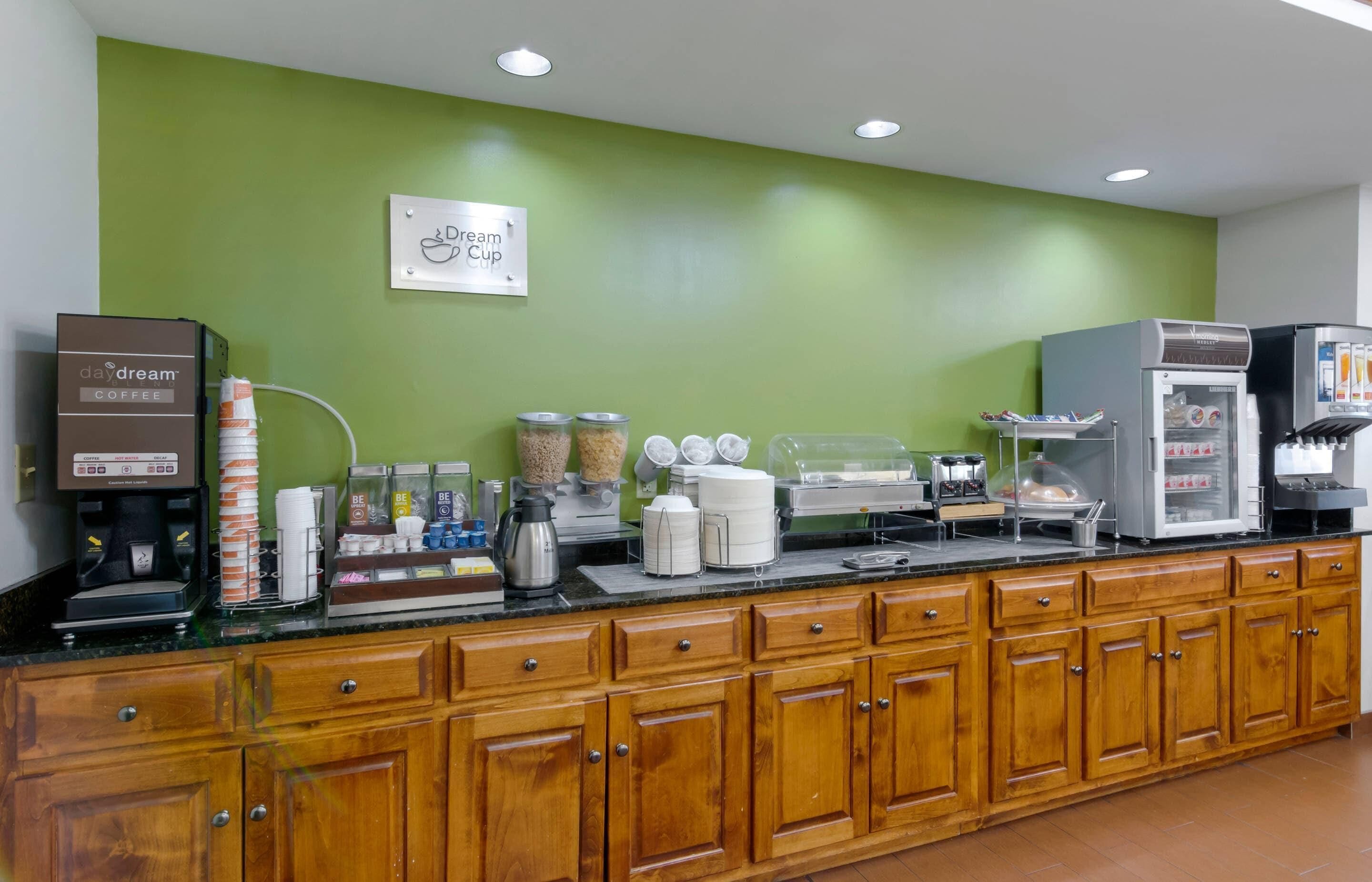 A coffee station with a coffee machine, dispensers, and a refrigerator.
