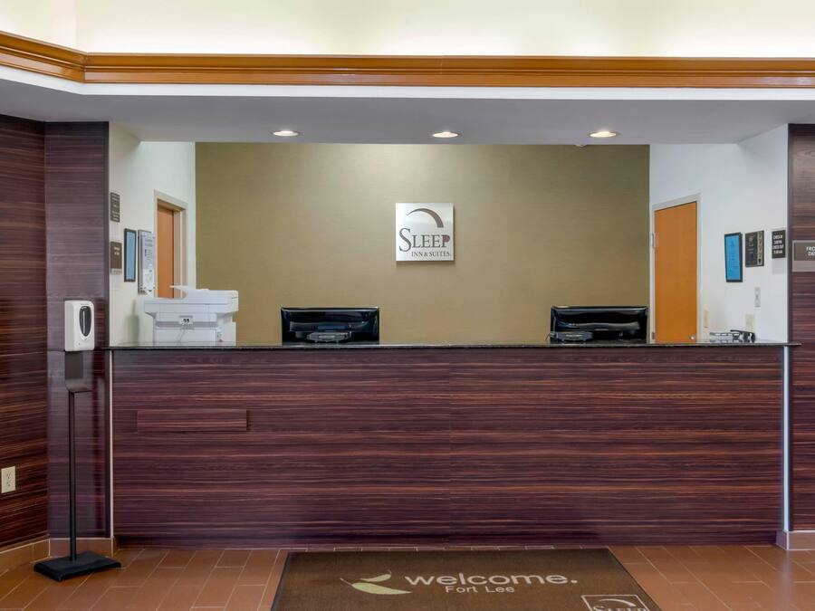 Un comptoir d’accueil avec une enseigne « Sleep Inn & Suites », un paillasson et une pancarte indiquant « Réception ».