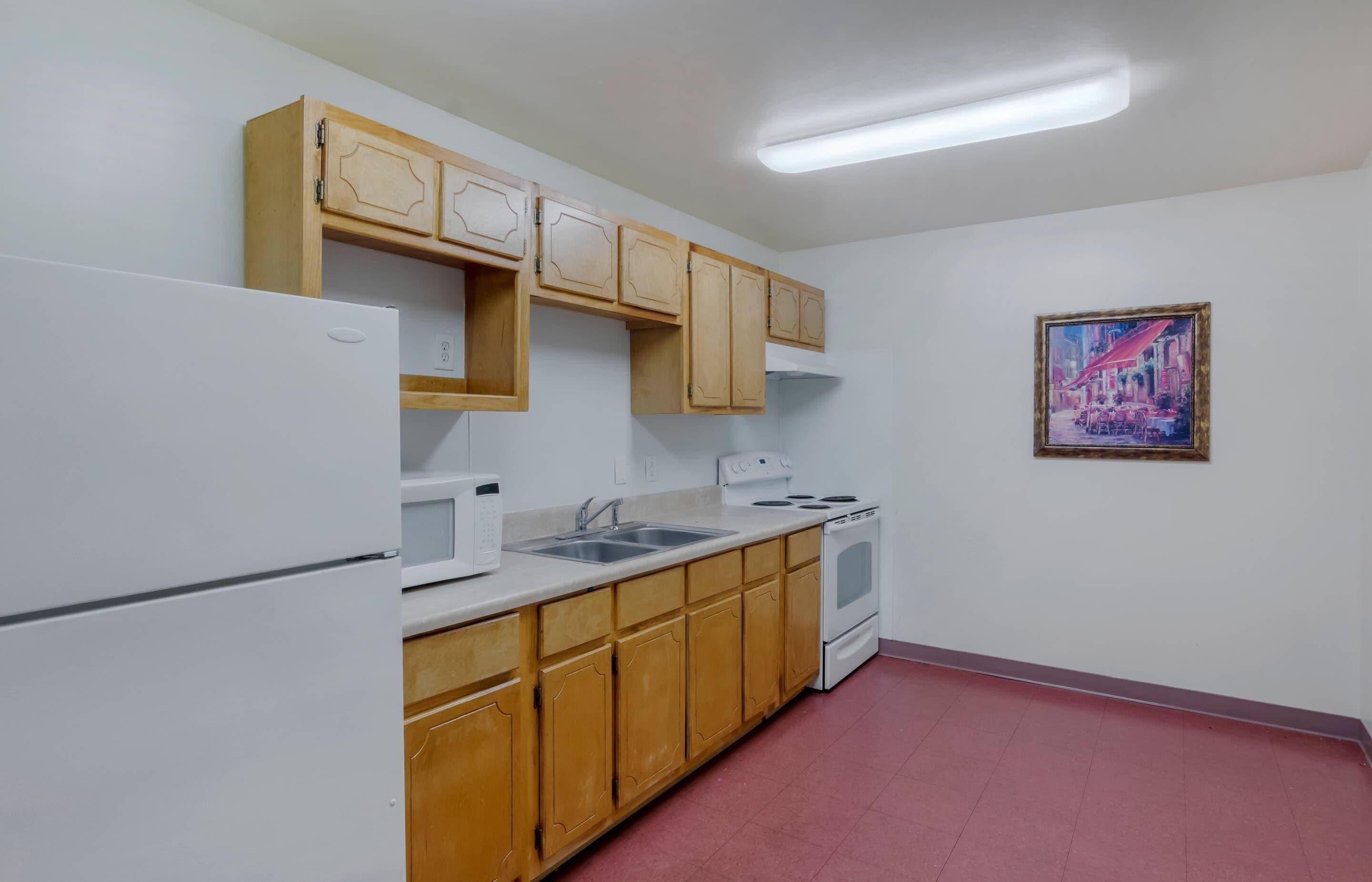 A kitchen with wooden cabinets, a white refrigerator, a microwave, a sink, and a stove.