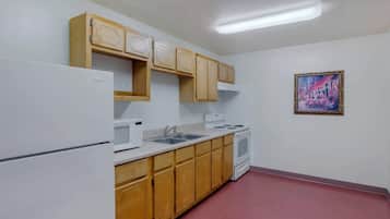 A kitchen with wooden cabinets, a white refrigerator, a microwave, a sink, and a stove.