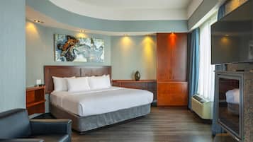 A modern hotel room with a large bed, a desk, a television, and a painting on the wall.