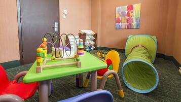 Kids can play and explore at this hotel room's play area, featuring a play table with toys and a colorful tunnel.