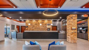A modern hotel lobby with a reception desk, stone accent walls, and seating area. - Quality Inn & Suites Levis (Levis)