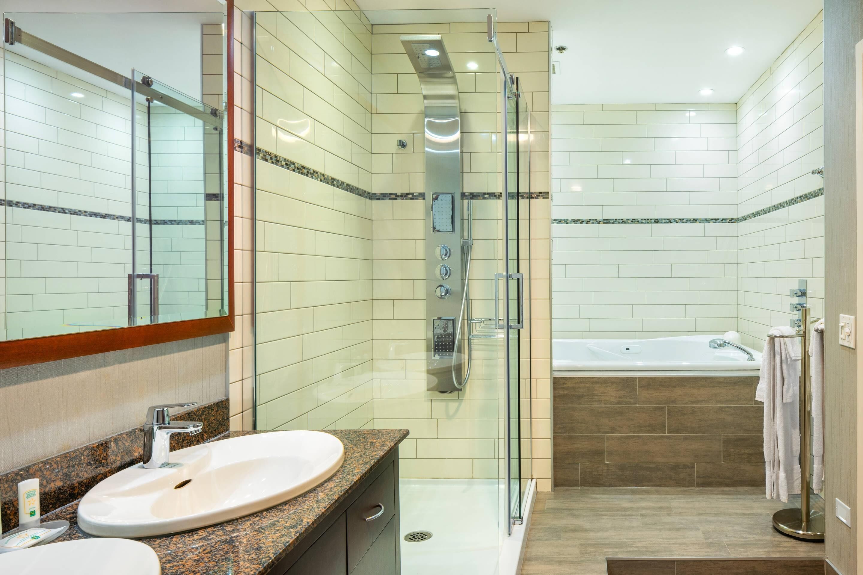A modern bathroom with a glass-enclosed shower, a standalone bathtub, and a granite countertop sink.