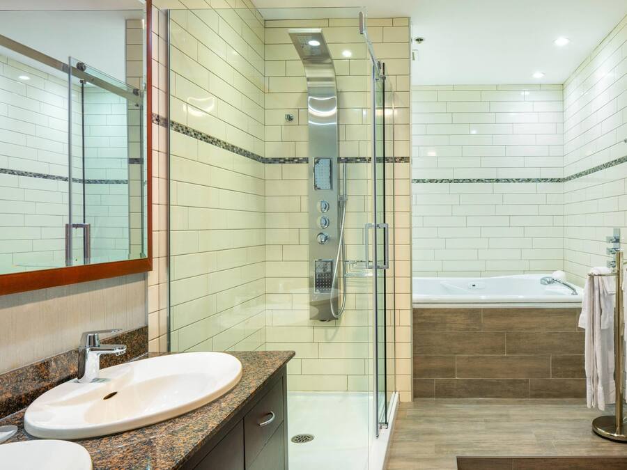 A modern bathroom with a glass-enclosed shower, a standalone bathtub, and a granite countertop sink.