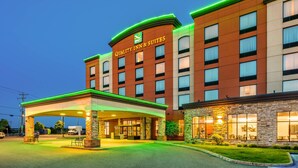 A hotel with a prominent sign reading "Quality Inn & Suites," featuring a modern design with a brick facade and green lighting accents. - Quality Inn & Suites Levis (Levis)
