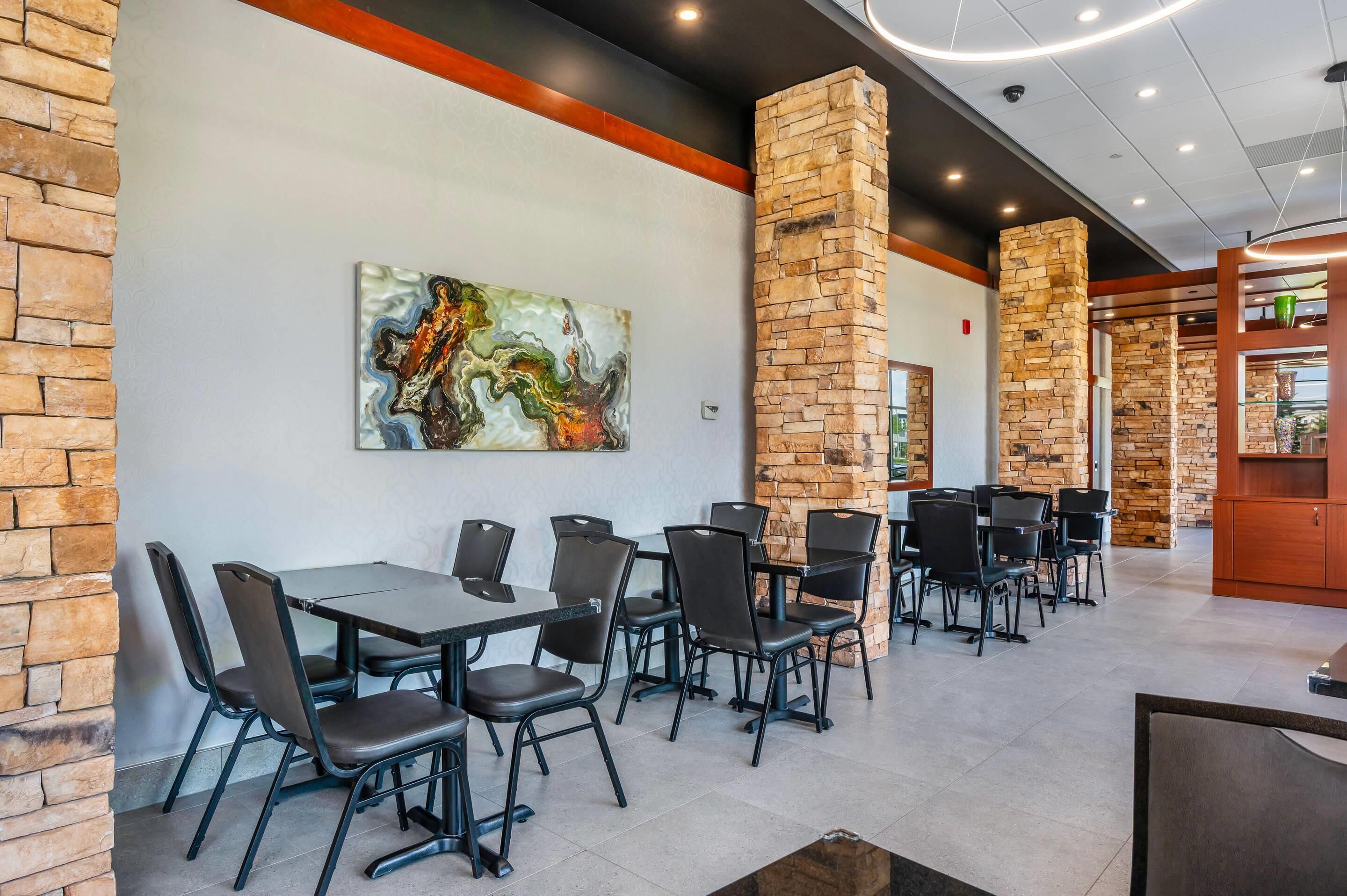 Een restaurant met bakstenen muren, moderne tafels en stoelen.