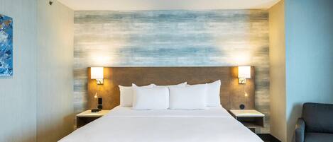 A hotel room with a large bed, two bedside tables, a chair, and a wall with a textured design.
