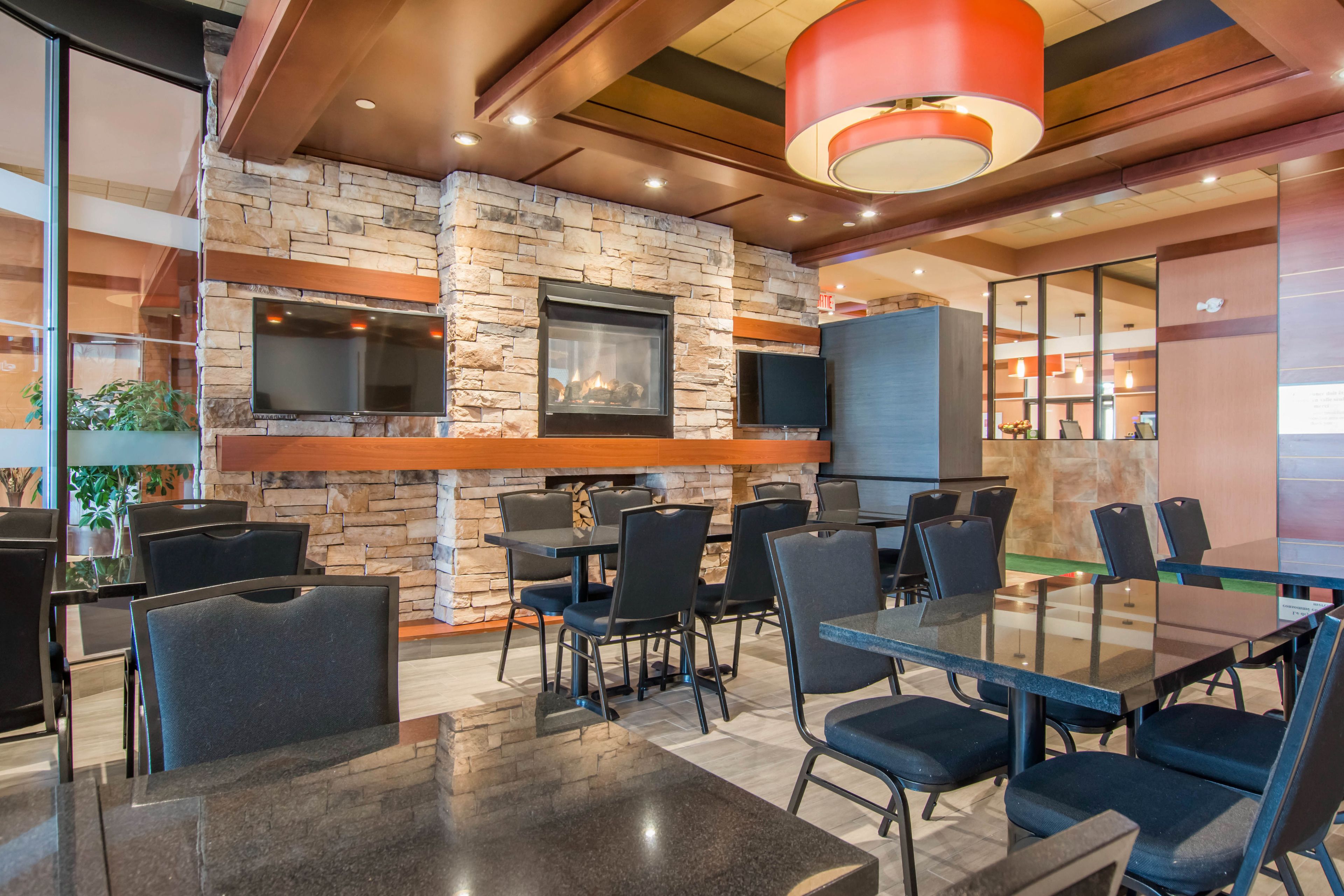 A modern restaurant with stone walls, a fireplace, and multiple tables and chairs.