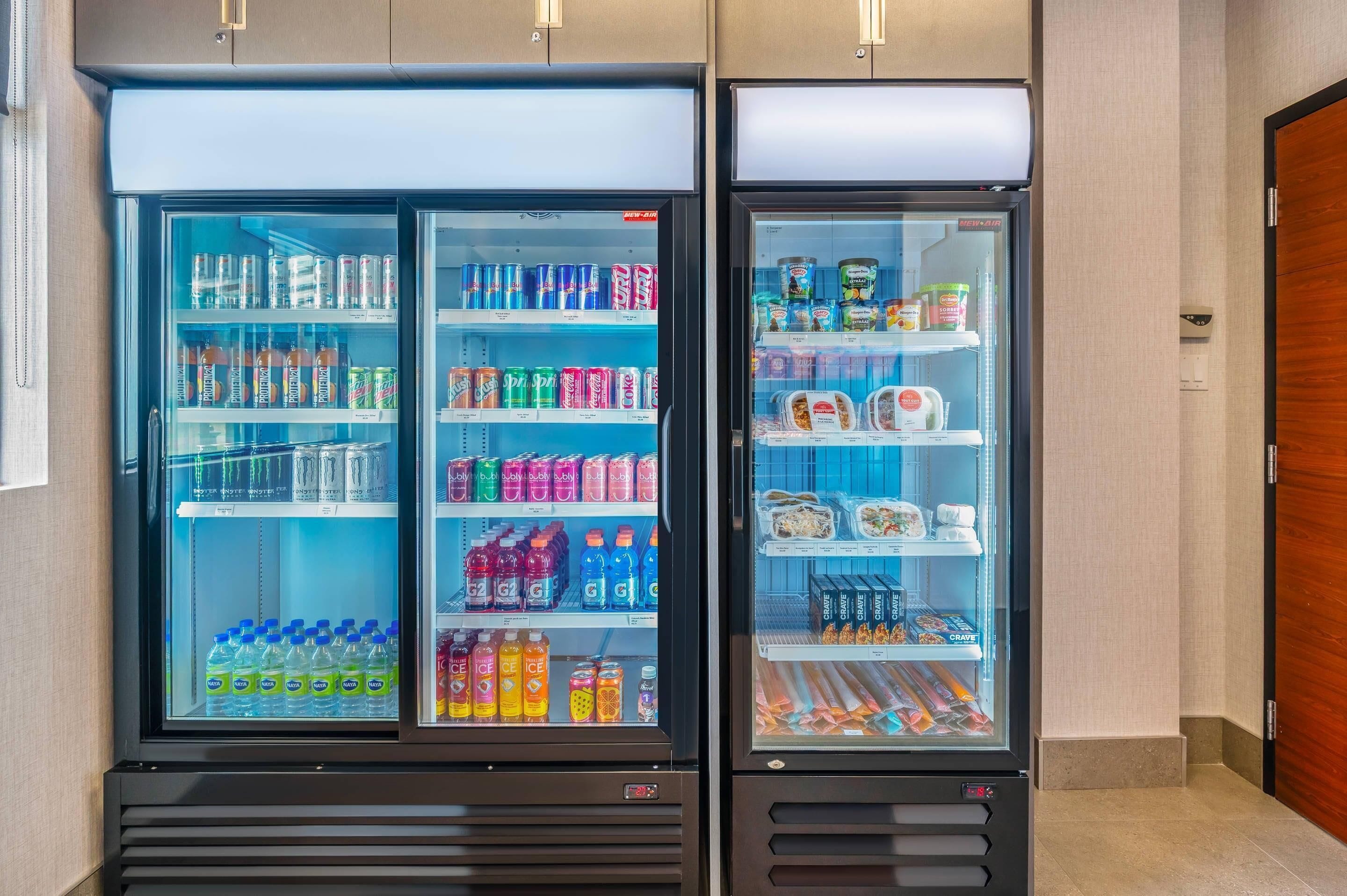 Two refrigerated beverage dispensers stocked with various drinks and snacks.