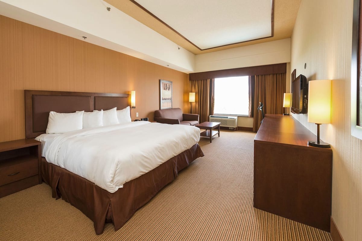 Ein Hotelzimmer mit einem großen Bett, einem Schreibtisch, einem Stuhl und einem Fernseher.