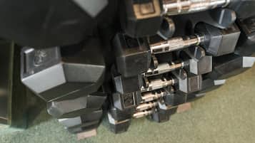 A close-up of a set of black dumbbells with metallic handles and weight plates, arranged on a green surface.