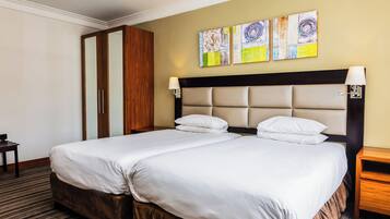 Une chambre d’hôtel avec deux lits, une armoire en bois et des œuvres d’art abstraites accrochées au mur.