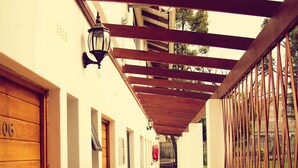 A corridor with wooden benches, a metal railing, and a wooden door with the number 106. - Premier Splendid Inn Pinetown (Pinetown)