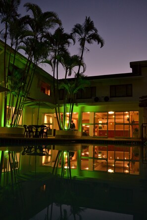 A hotel with a pool, palm trees, and a sunset view.