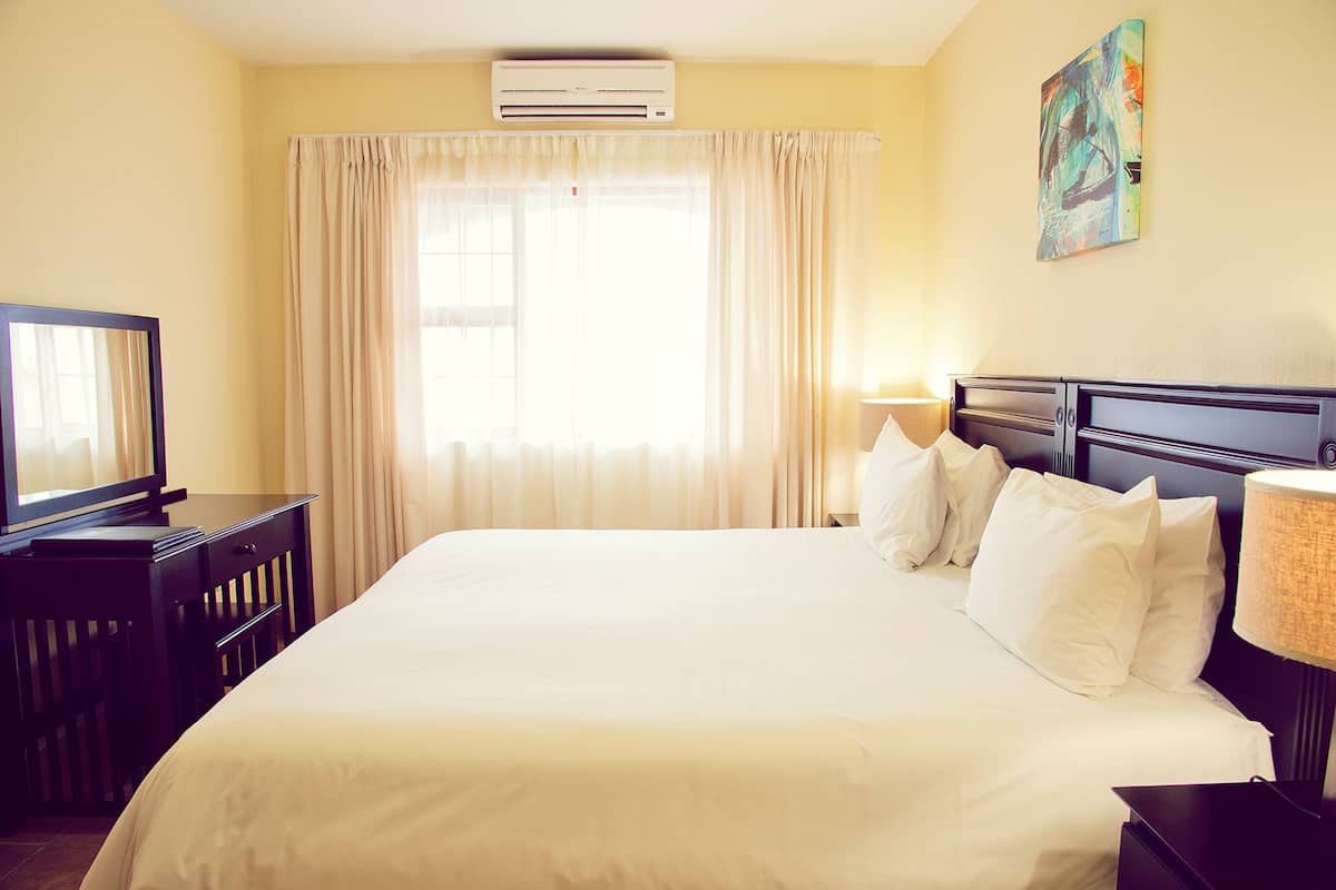 A hotel room with a bed, a television, a desk, and a window with curtains.