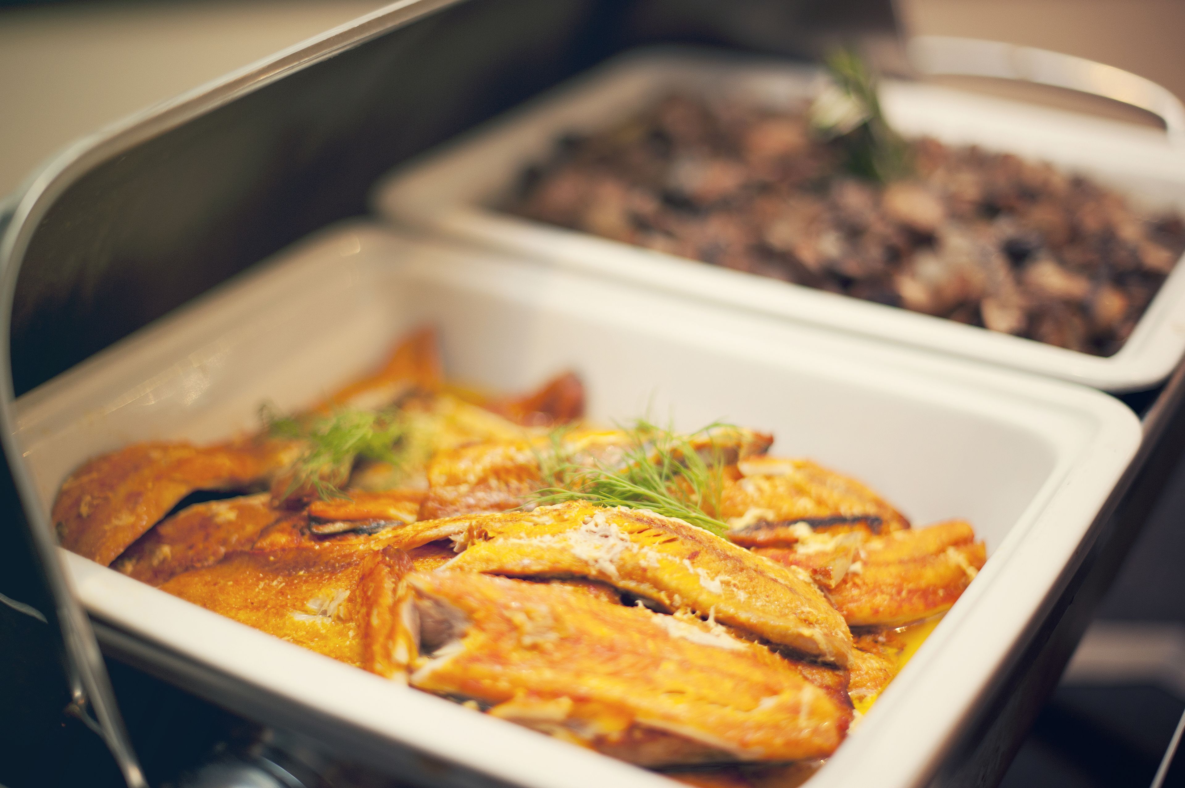 A buffet with various dishes, including a section with what appears to be roasted chicken and another with a different type of food, possibly a casserole or salad.