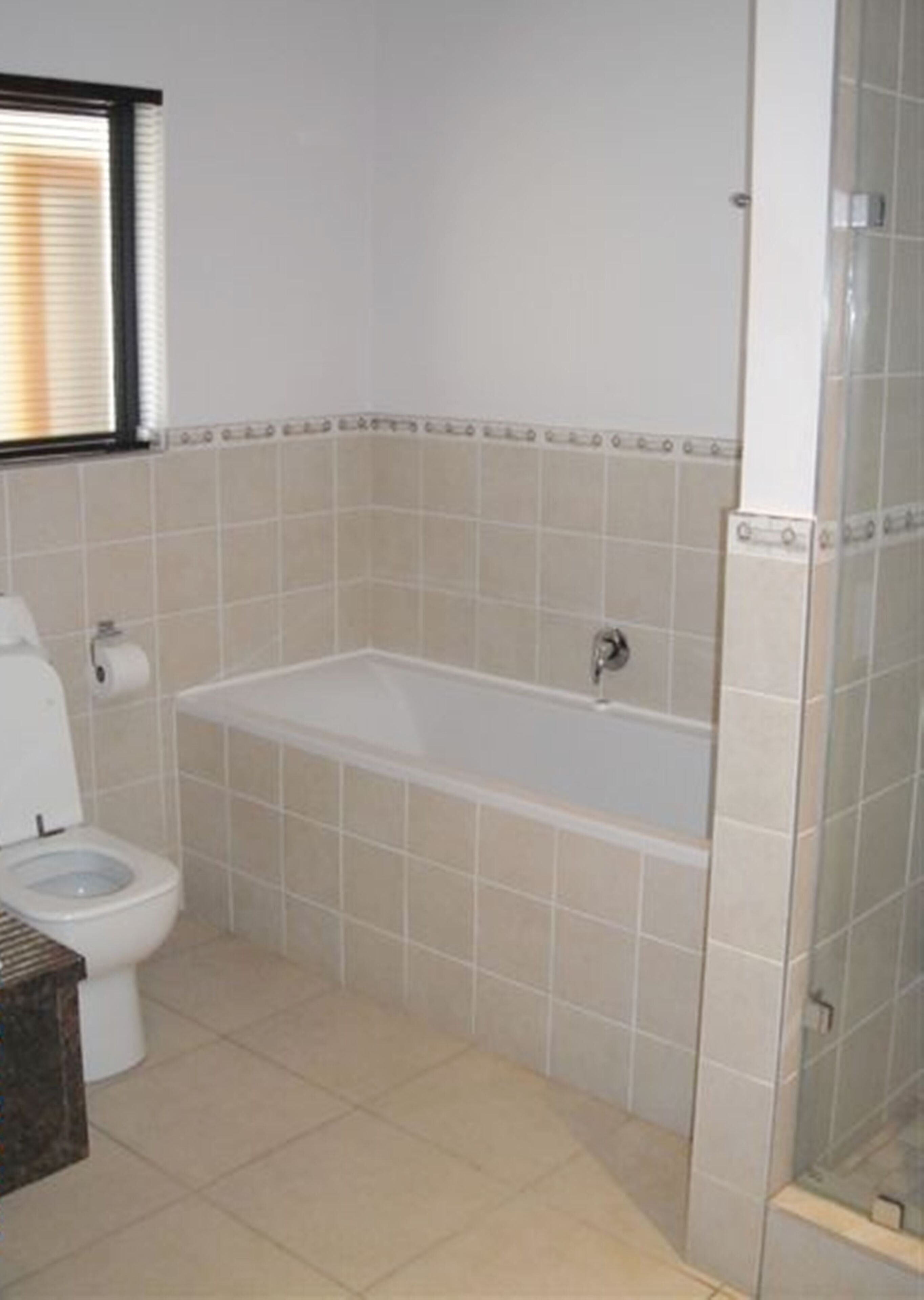 A bathroom with a toilet, a bathtub, and a shower area.