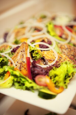 A close-up of a salad with various vegetables and a piece of grilled fish.