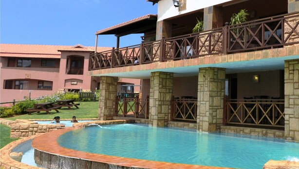 A hotel with a pool, outdoor seating, and a stone facade. - The Edwardian (Port Edward)