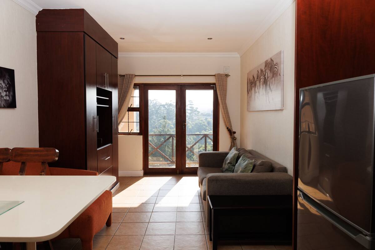 A modern kitchen with a dining table, a sofa, and a refrigerator.