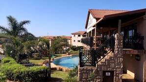 A hotel with a pool, a stone staircase, and a view of the surrounding landscape. - The Edwardian (Port Edward)