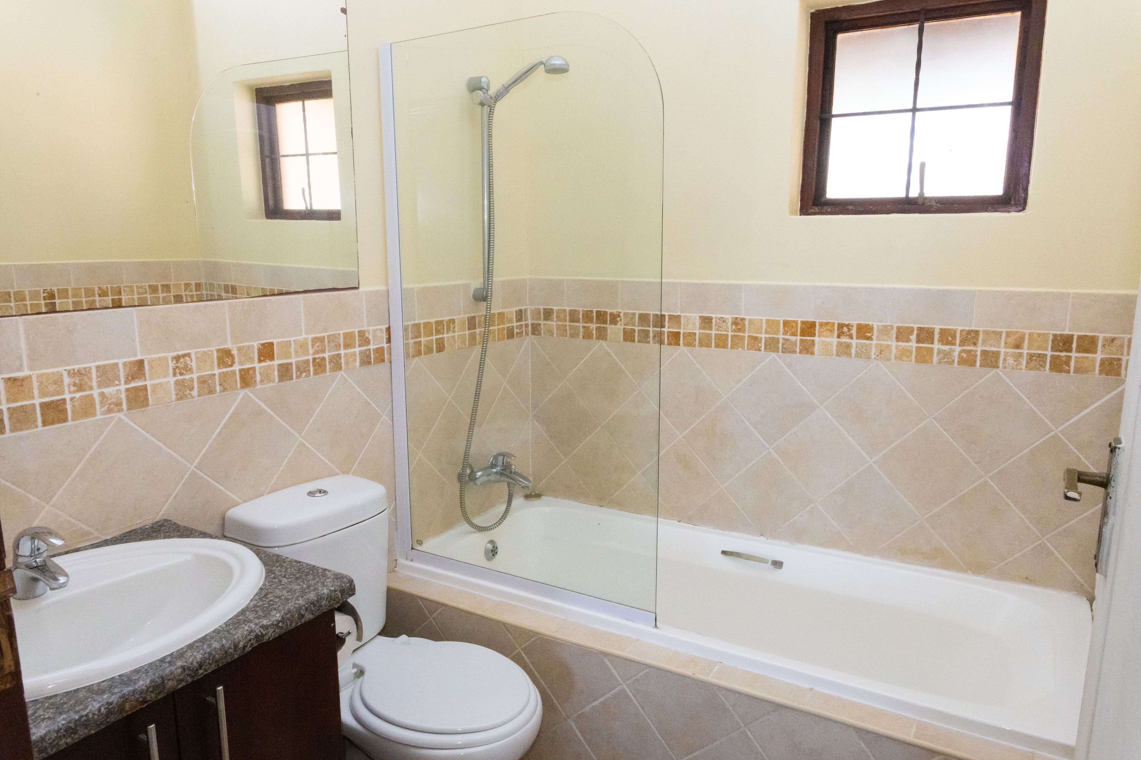 A bathroom with a glass-enclosed shower, a toilet, and a sink.