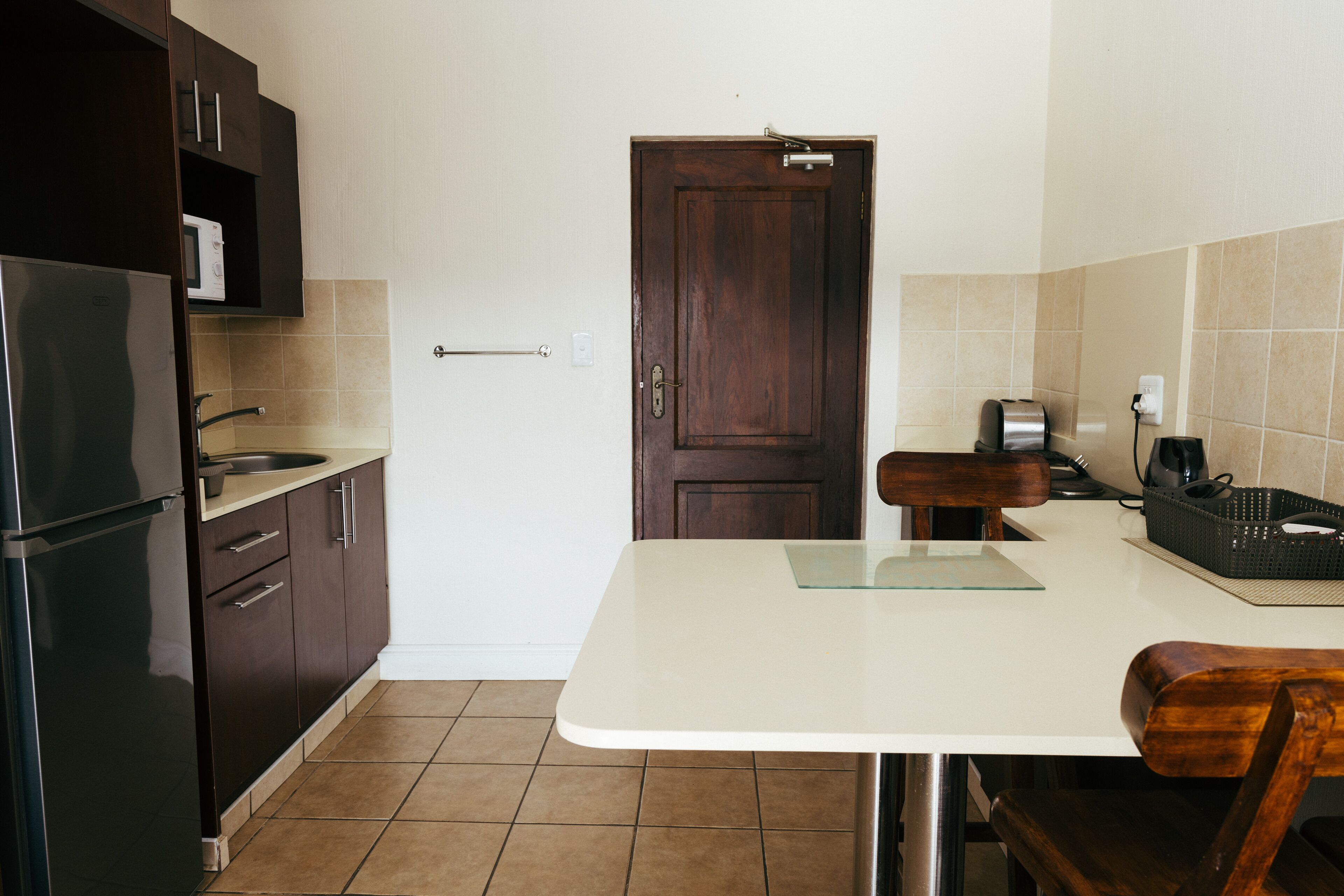 A kitchen with a refrigerator, microwave, sink, and wooden cabinets.
