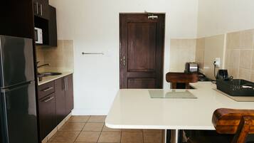 A kitchen with a refrigerator, microwave, sink, and wooden cabinets.