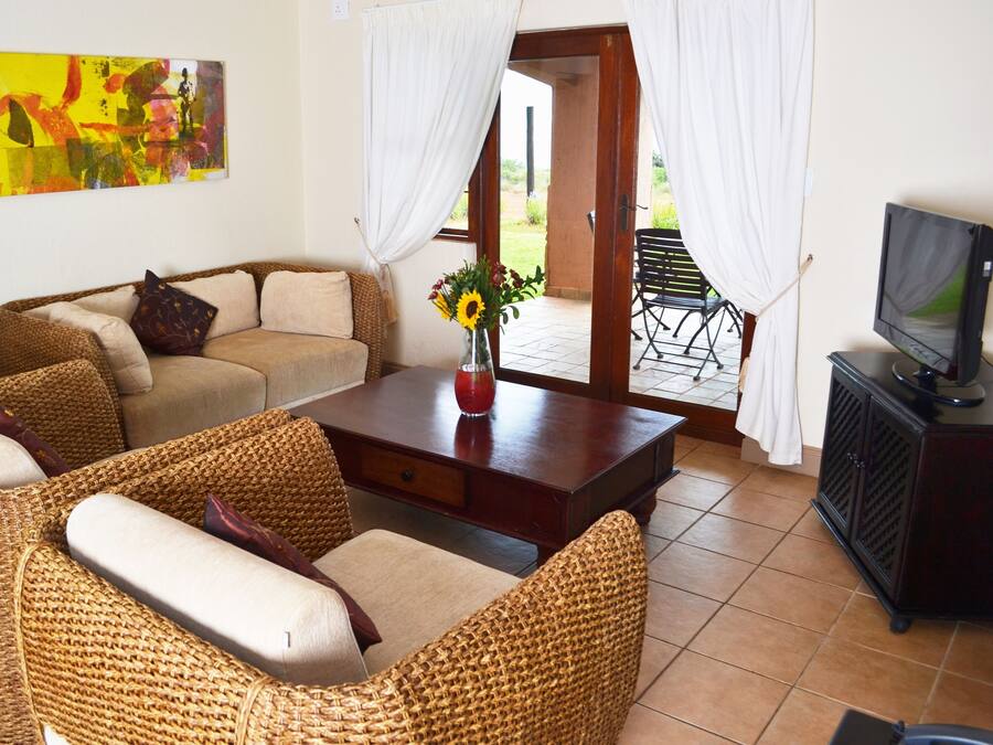 Una sala de estar con muebles de mimbre, una mesita de centro, un televisor y un cuadro en la pared.