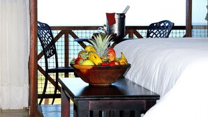 A wooden table with a fruit bowl and a metal pot on a balcony with a bed and chairs. - The Edwardian (Port Edward)